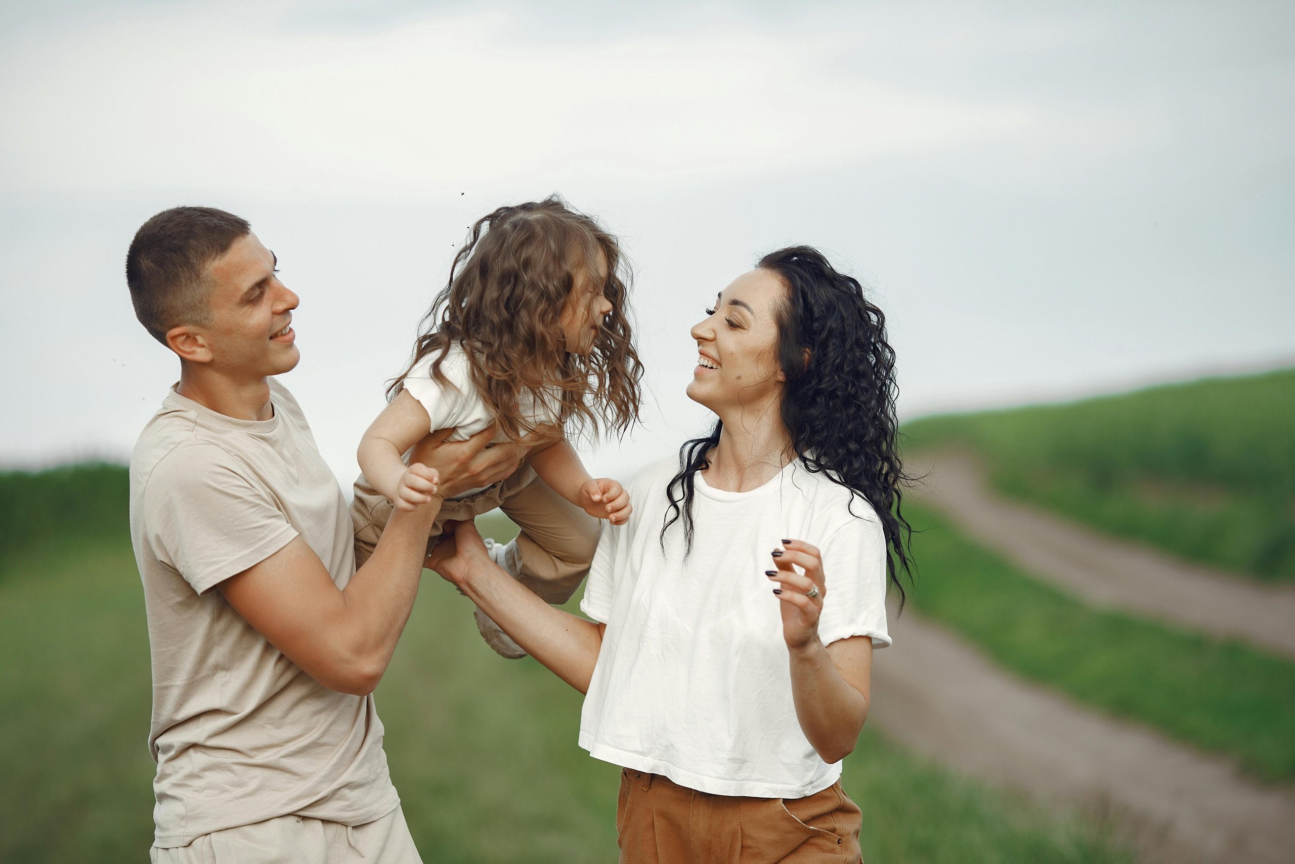 A joyful family moment outdoors with parents playing with their daughter.