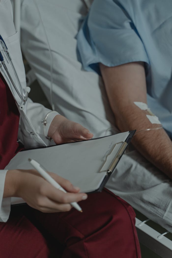 A doctor taking notes while sitting beside a patient in a hospital bed